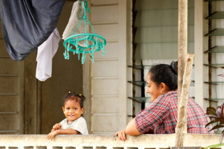 Neiafu, Tonga - November 14, 2013: Tongan woman with a child sitting on a front porch of her house, Neiafu, Vavau island, Tonga